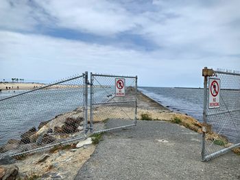 Road sign by sea against sky