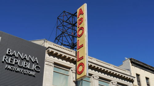 Low angle view of sign on building against blue sky