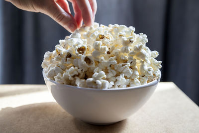 Bowl of freshly made popcorn with hand reaching to it