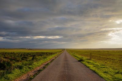 Road amidst field against sky