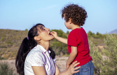 Complicity and play between mother and son feeding a cherry directly into mother's mouth