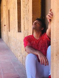 Man sitting on wall of building