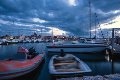 Sailboats moored at harbor against sky