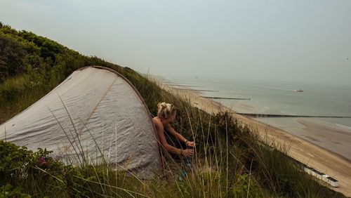 Woman in tent on mountain against beach