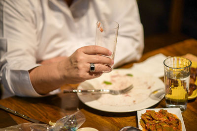 Close-up of hand holding drink served on table