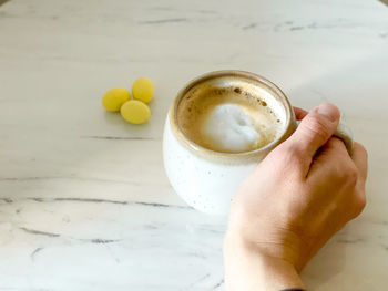 Cropped image of hand holding coffee cup on table