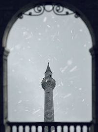 Low angle view of tower seen through window during snowfall