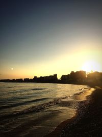 Scenic view of beach against clear sky during sunset