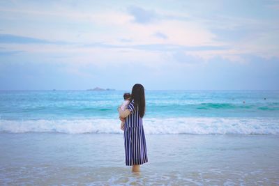 Woman standing at beach against sky