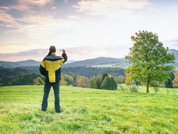 Rear view of man standing on field against sky