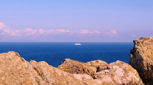 Rock formations by sea against blue sky