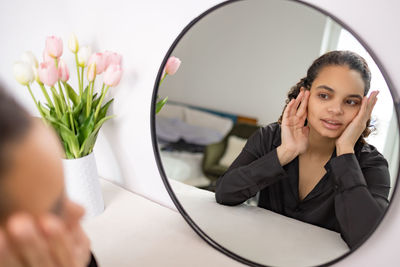 Portrait of young woman sitting on mirror