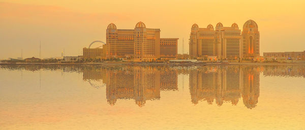 Reflection of buildings in lake during sunset