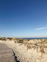 Scenic view of beach against clear blue sky