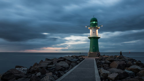 Lighthouse by sea against sky