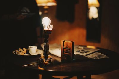 Close-up of illuminated light bulb on table in restaurant