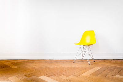 Yellow chair on parquet floor against wall at home