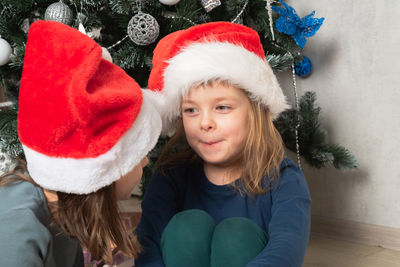 Portrait of smiling friends with christmas tree at home