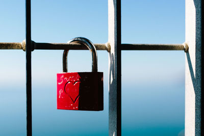 Close-up of padlocks on railing against sky