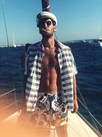 Portrait of man smoking while standing in boat over sea against sky