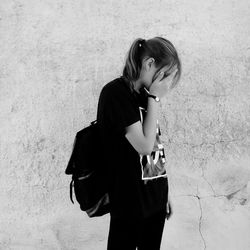 Young woman standing against wall