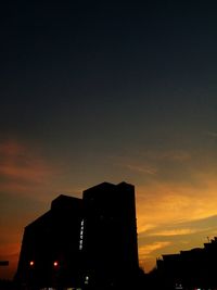 Low angle view of silhouette built structures against sky at sunset