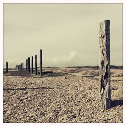 Fence on field against cloudy sky