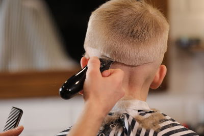Men's hairstyling, haircutting, in a barber shop or hair salon. grooming kid boy hair in barber shop