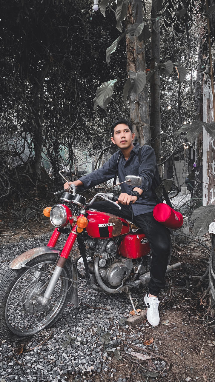 PORTRAIT OF MAN RIDING MOTORCYCLE ON TREE