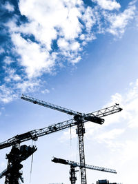 Low angle view of cranes at construction site against sky