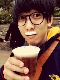 Close-up portrait of a smiling young man holding drink