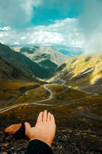 Cropped hand against mountains