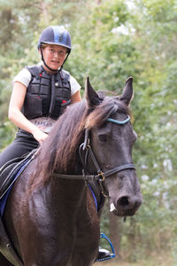 Portrait of woman riding horse at forest