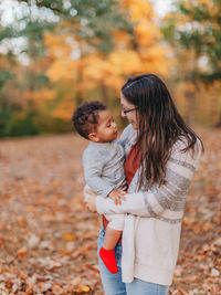 Mother and son standing in park during autumn