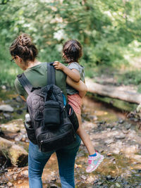 Rear view of mother and daughter walking in forest