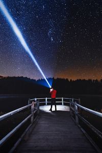 Man with flashlight standing on pier against star field at night