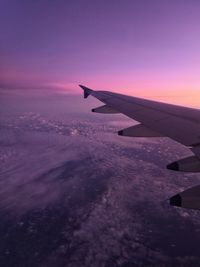 Airplane wing against sky during sunset