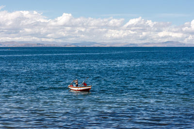 Men sailing on sea against sky