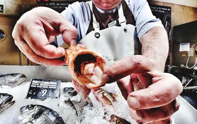 Midsection of man holding fish in kitchen