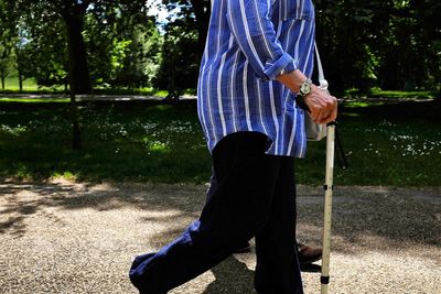 Low section of man with umbrella standing by tree