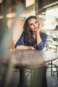 Portrait of young woman sitting on table in restaurant