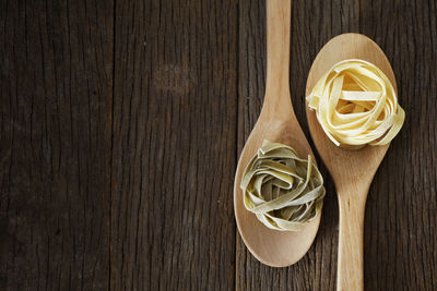 Close-up of tagliatelle pasta in wooden spoons on table