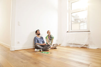 Young couple sitting on floor in empty apartment