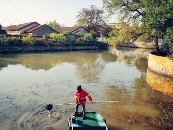 Rear view of man on lake against trees