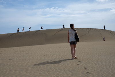 People walking on desert against sky