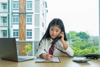 Businesswoman talking on telephone at desk in office