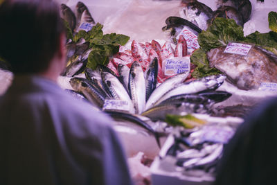Rear view of man selling fish at market stall