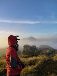 Side view of man standing on mountain against sky