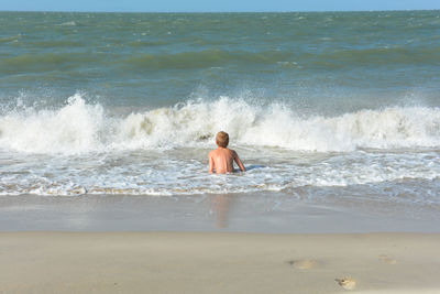 Rear view of shirtless man on beach