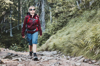 Woman with backpack hiking in mountains, spending summer vacation close to nature